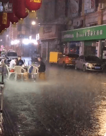 폭우 속 야외 테이블에서 술을 마시는 중국 남자 3명